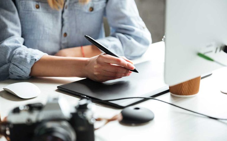 Person using a stylus on a graphic tablet at a desk.