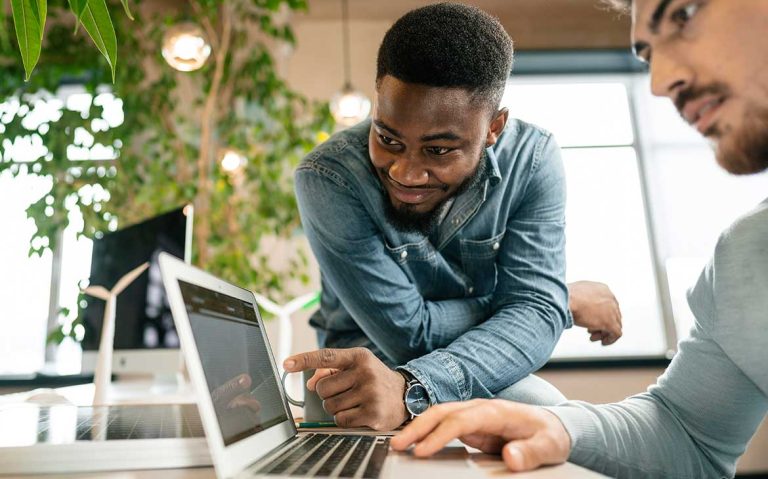 A man enthusiastically pointing at a laptop screen during a discussion.
