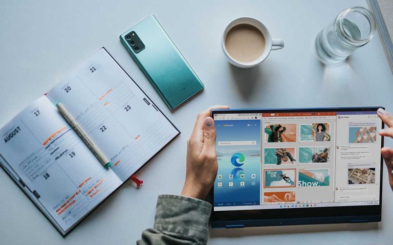 Person using a tablet with a cup of coffee and planner nearby.