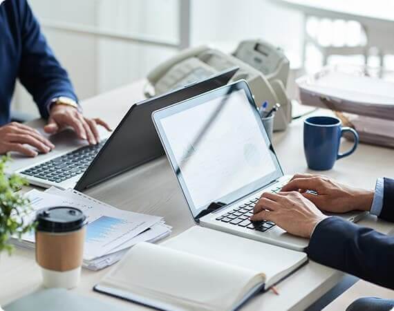 Two people working on laptops in a bright office space.