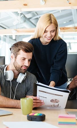 Two colleagues reviewing a document together in an office.