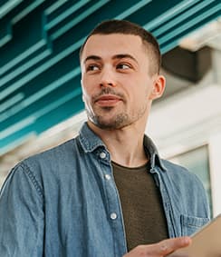 Portrait of a young man in a denim shirt looking to the side.