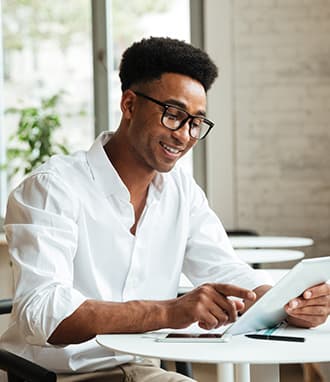 A man smiling while using a tablet.
