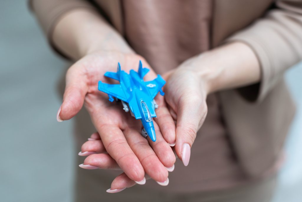Person holding a small blue toy jet in their hands.