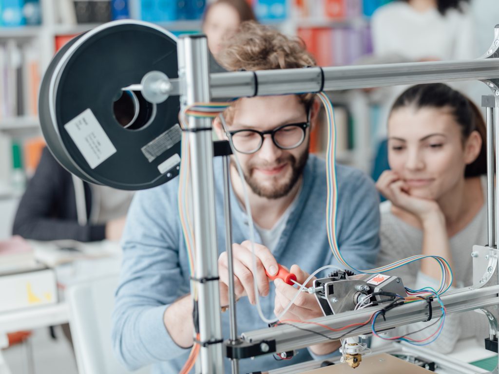 Two people working on a 3D printer together.