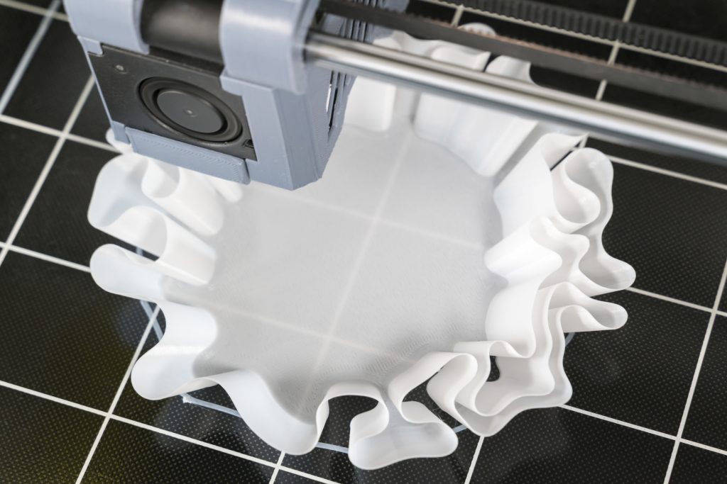3D printer creating a white, ruffled fabric-like object.
